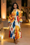 Woman wearing a colorful floral dress in an indoor setting with decorative elements.