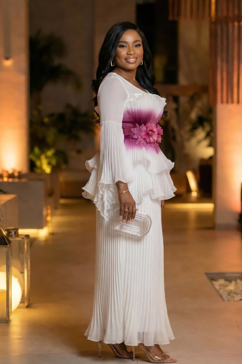Woman in a white dress with floral details standing in an elegant indoor setting.