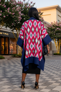 Woman wearing a colorful patterned cardigan in an outdoor shopping area.