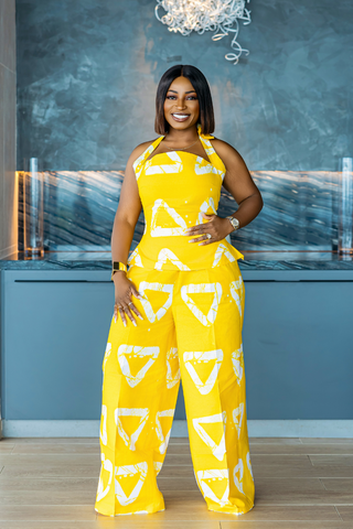 Woman in a yellow patterned jumpsuit standing in a modern kitchen.