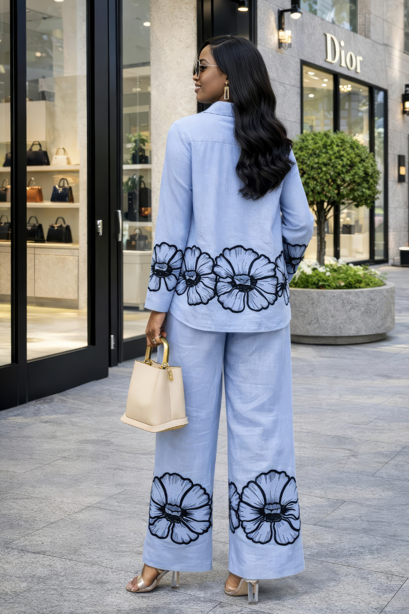 Woman wearing a light blue outfit with floral patterns in front of a store.