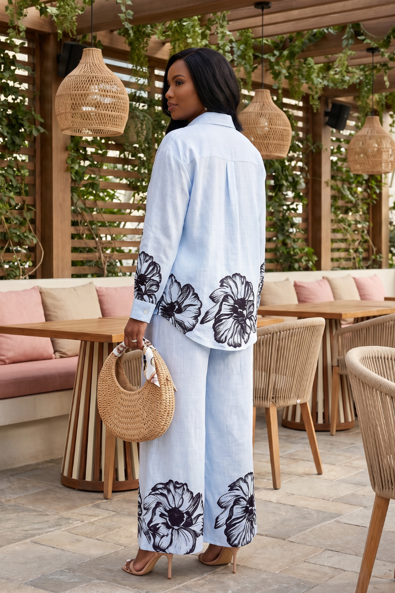 Woman in a light blue floral outfit standing in an outdoor cafe setting.