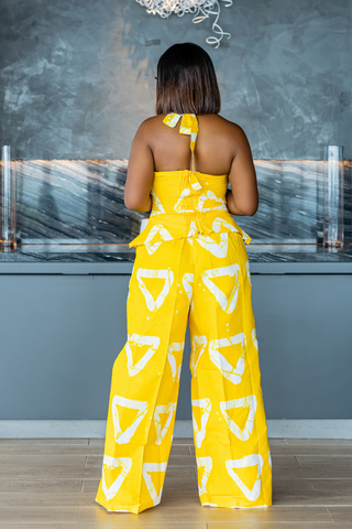 Woman wearing a yellow and white patterned jumpsuit in a kitchen setting