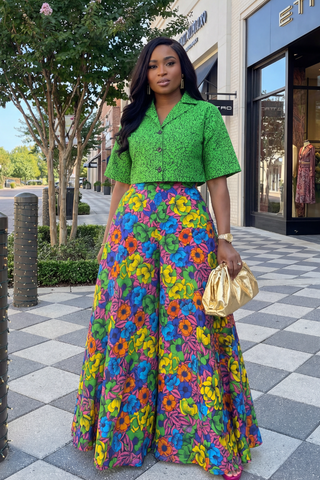 Woman in a green top and colorful floral skirt standing on a checkered sidewalk.