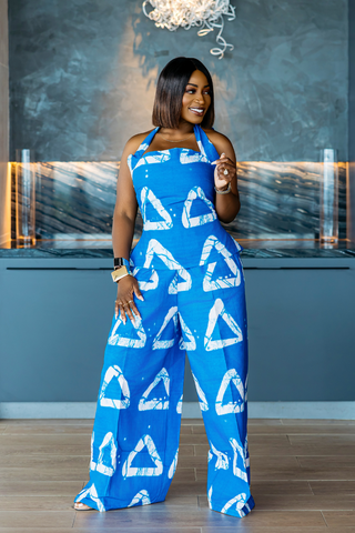 Woman wearing a blue jumpsuit with white triangle patterns indoors.