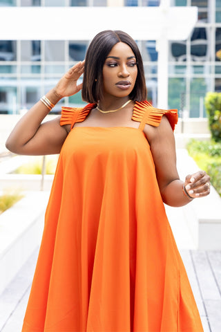 Woman wearing an orange dress with a blurred outdoor background