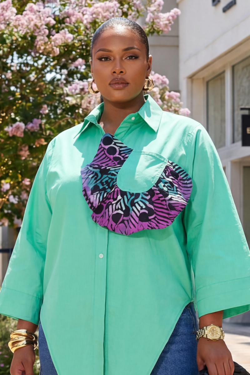 Woman wearing a teal shirt with a colorful scarf around her neck, standing outdoors.