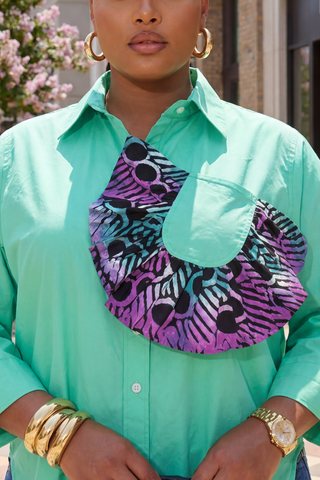 Person wearing a turquoise shirt with a colorful patterned scarf, gold jewelry, and hoop earrings.