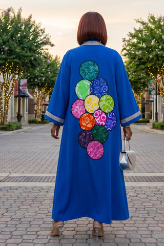 Person wearing a blue dress with colorful circular patterns walking on a street.
