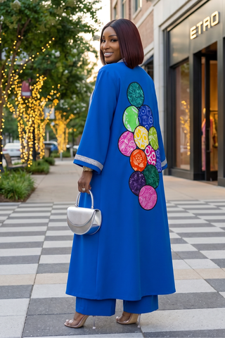 Woman wearing a blue coat with colorful circular patterns on a city street.