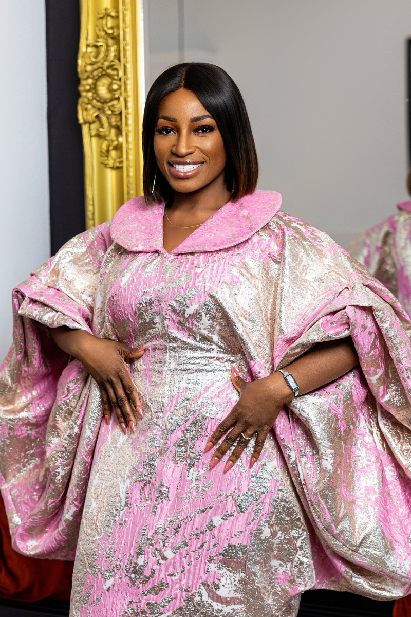 Woman wearing a pink and silver traditional outfit with a gold frame in the background