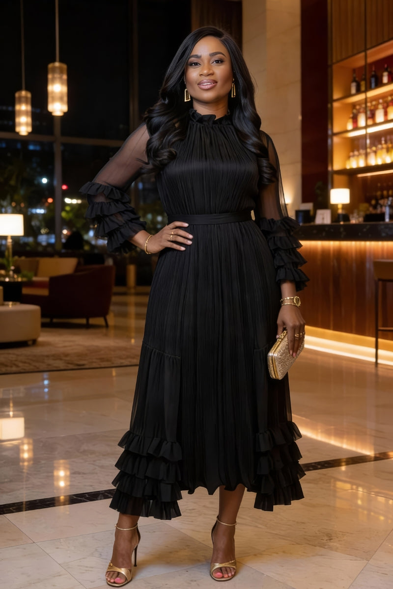 Woman in a black ruffled dress standing in an elegant indoor setting.