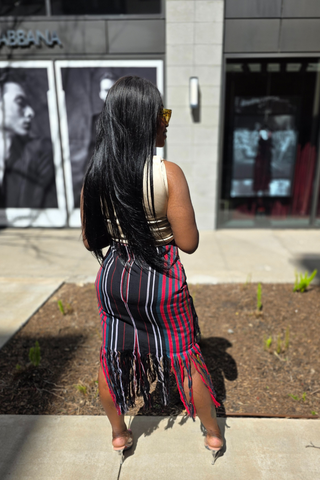 Woman in a striped dress standing on a sidewalk with a store facade in the background