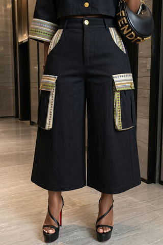 Person wearing black pants with colorful accents and a Fendi handbag indoors.