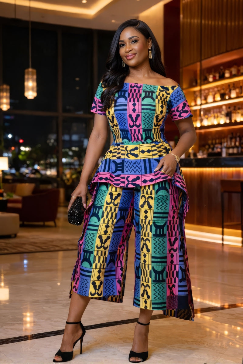 Woman in a colorful patterned outfit standing in an elegant indoor setting.