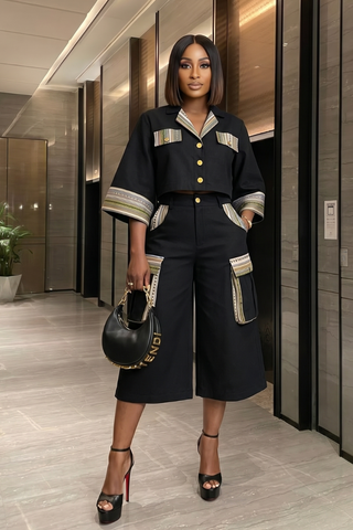 Woman in a stylish black outfit with gold accents in an indoor setting