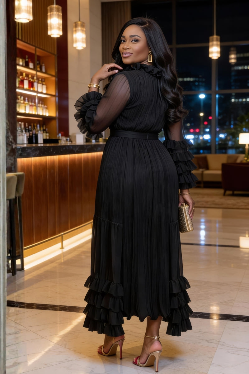 Woman in a black dress standing in a stylish indoor setting with decor elements.