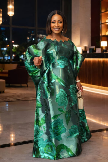 Woman in a green floral dress standing indoors with blurred background