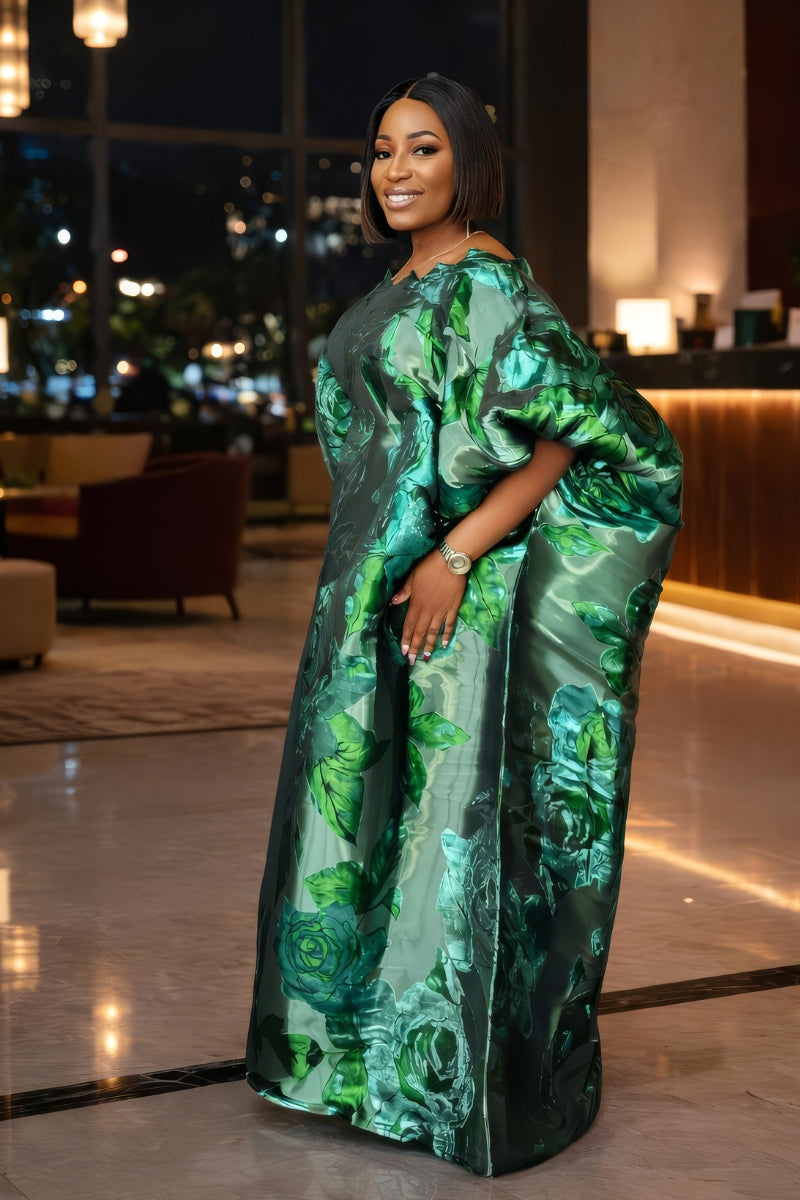 Woman in a green floral dress standing in an indoor setting with blurred background