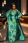 Woman in a green floral dress walking indoors with blurred background