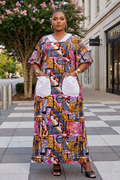 Woman in a colorful patterned dress standing on a city street with a building and tree in the background.