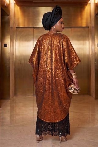 Woman in a bronze dress with black lace hem standing in an elevator.