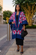 Woman wearing a colorful kimono-style coat in an urban setting with decorative lights.