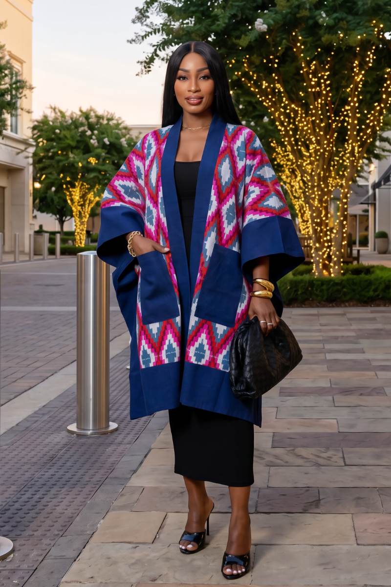 Woman wearing a colorful kimono-style coat in an urban setting with decorative lights.