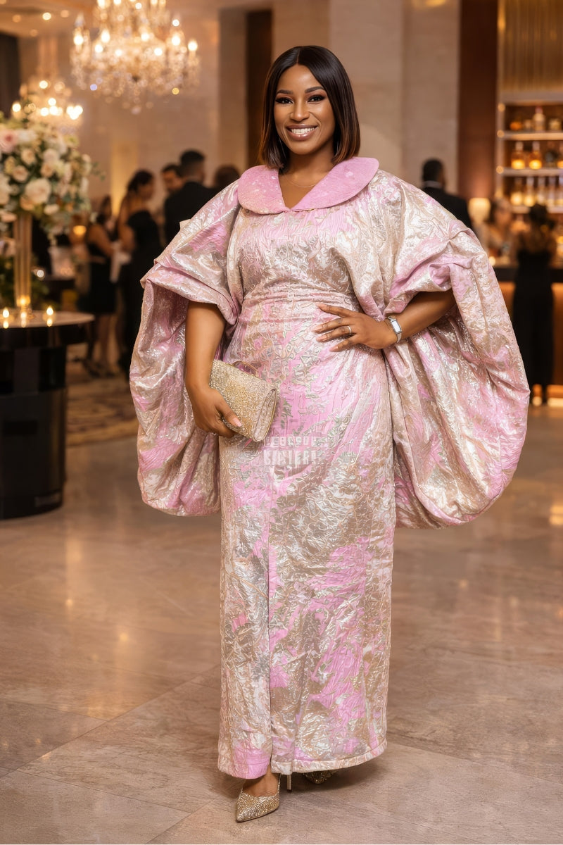 Woman in a pink and gold dress standing in an elegant indoor setting.