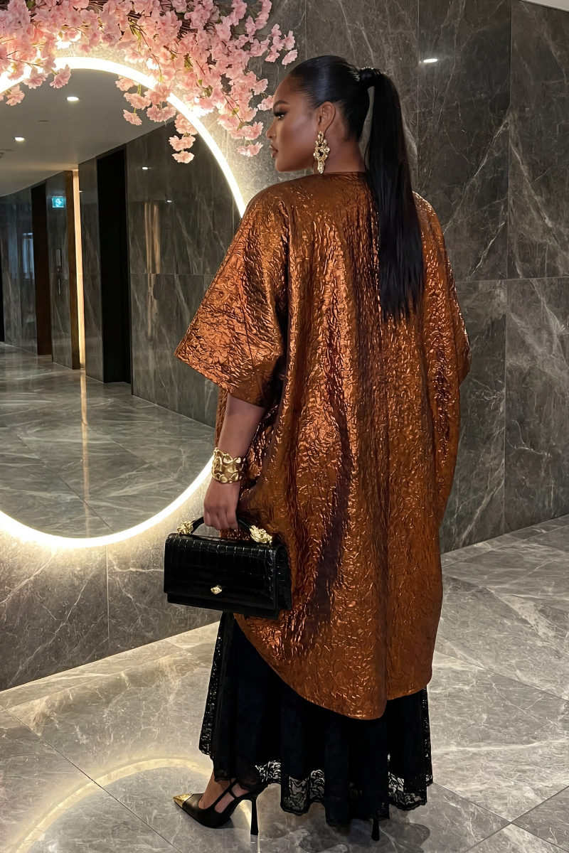 Woman in a brown textured dress holding a black handbag in a marble hallway.