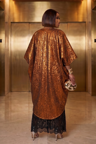 Woman in a bronze sequin dress standing in front of a gold elevator.
