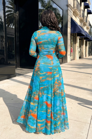 Woman wearing a colorful dress standing on a sidewalk with buildings in the background
