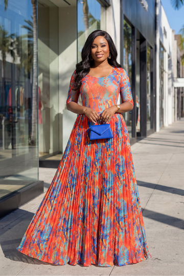 Woman in a colorful dress standing on a sidewalk with a building in the background