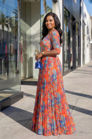 Woman in a colorful dress standing on a sidewalk with a building in the background