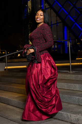 Woman in a red dress standing on steps at night.