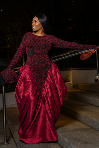 Woman in a burgundy evening gown standing on steps at night.