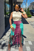 Woman wearing a colorful fringe skirt and beige top on a city street.