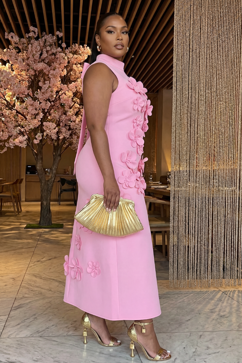 Woman in a pink floral dress standing in an elegant indoor setting.