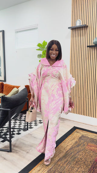 Woman in a pink and gold outfit standing in a luxurious hallway.